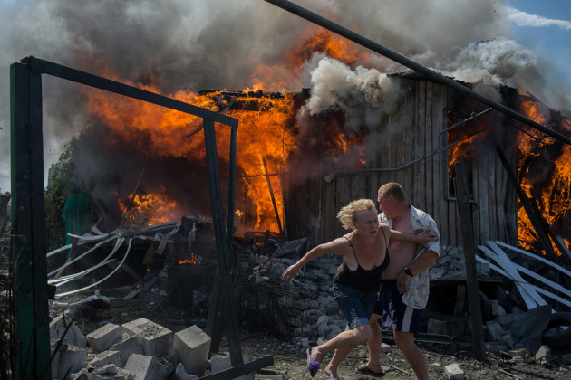 Photojournalism Single Image Winner. Civilians escape from a fire at a house destroyed by an air attack in Donbass, a village in Luhanskaya, eastern Ukraine, on 2 July 2014. Photo&nbsp;&copy; Valery Melnikov.